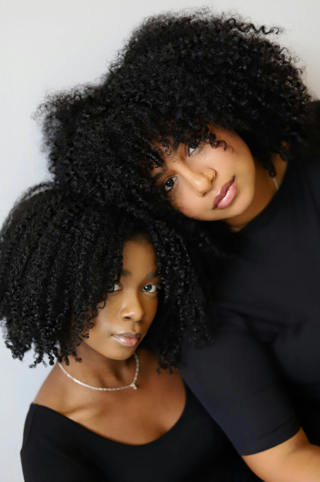 Two women with styled hair posing against a plain background